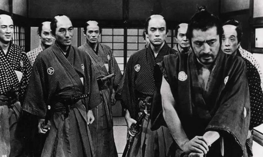 Sanjuro stands calm and disheveled in front of a crowd of clan retainers, from Akira Kurosawa's Sanjuro (1962)
