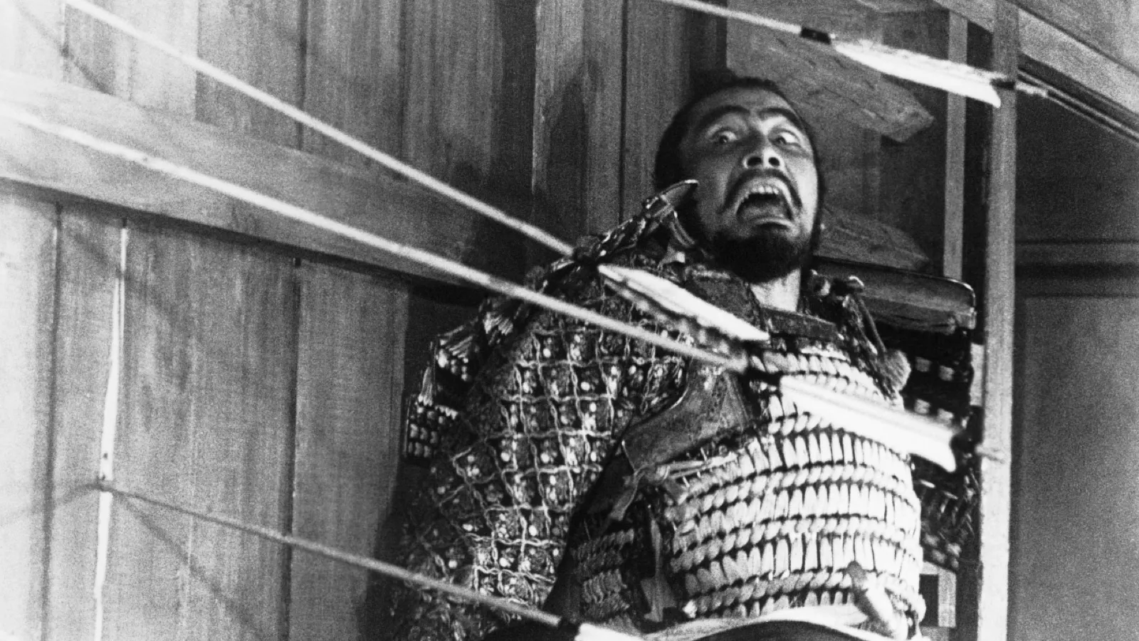 A samurai general pierced by arrows, mouth open in a final cry, in black and white